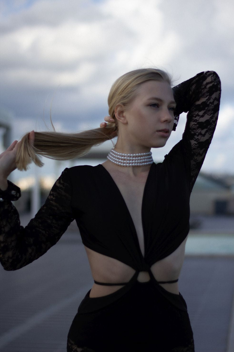 Model wearing Beverly black lace beach dress with deep neckline and sheer sleeves