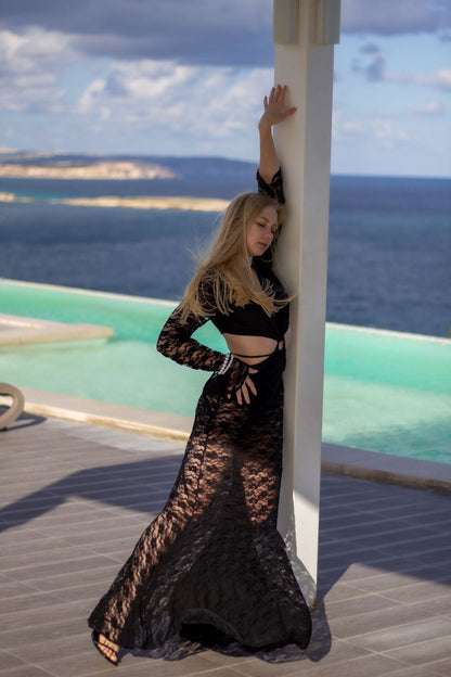Model wearing Beverly black lace beach dress with deep neckline and sheer sleeves
